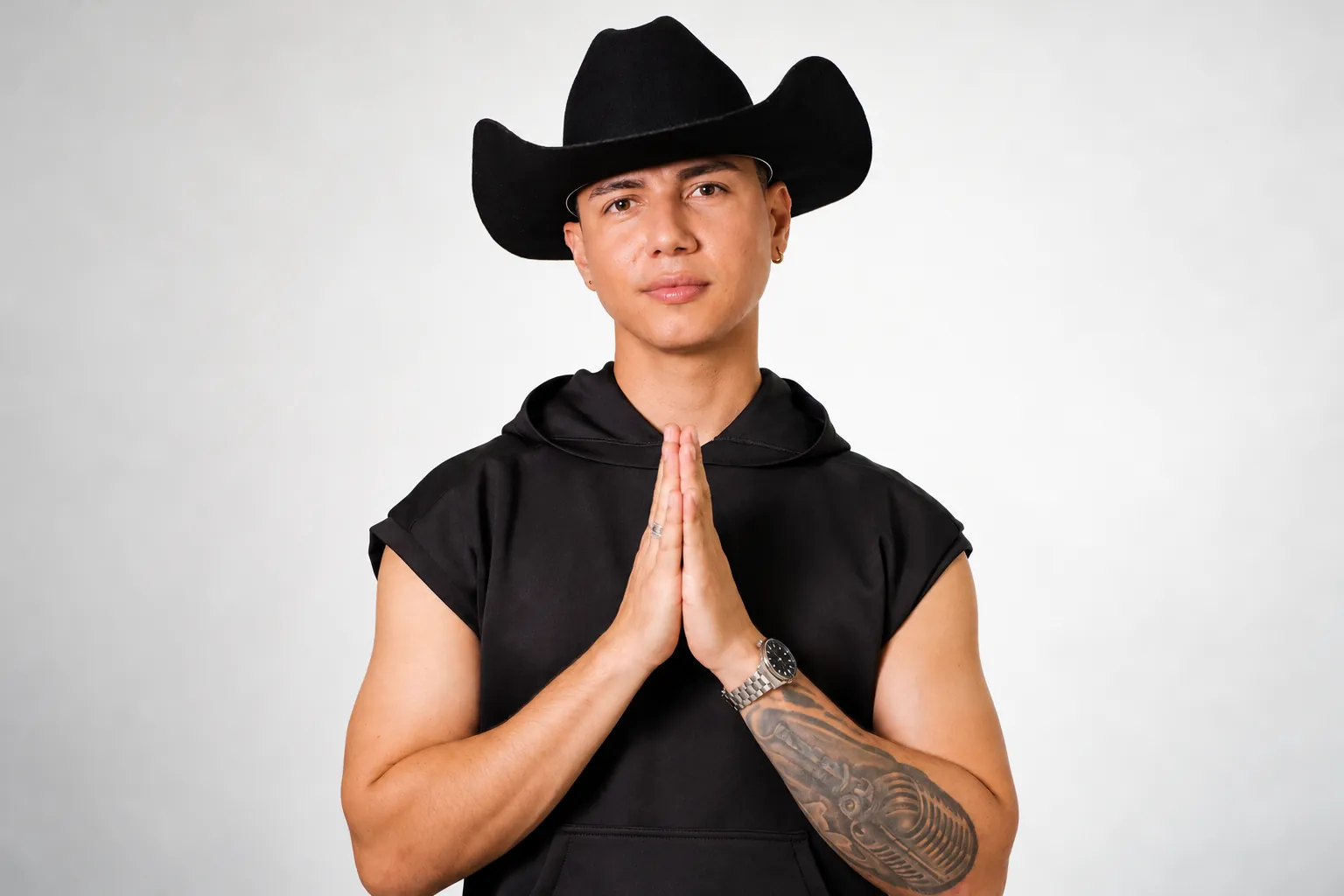 Retrato de Ryan Sanabria con sombrero negro y manos juntas